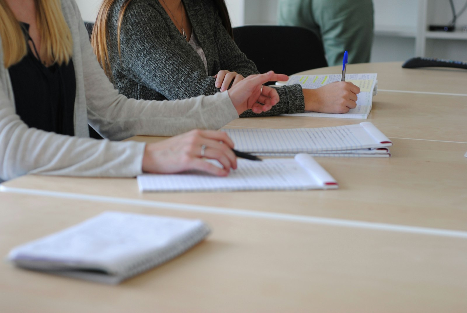 Des stagiaires prennent des notes à la main autour d'une grande table, carnets ouverts et stylos