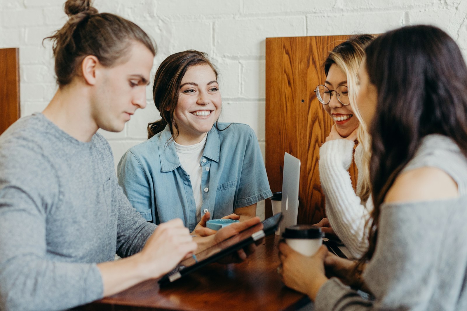 Un petit groupe de jeunes adultes souriants qui travaillent et échangent autour d'une table