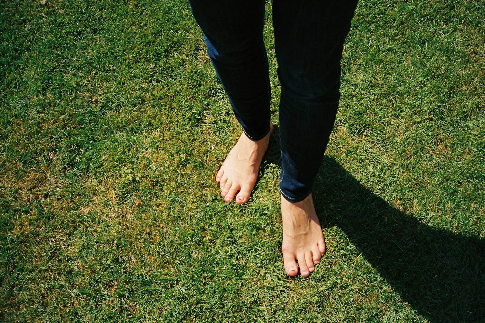 Une personne pieds nus marche dans l'herbe verte et ensoleillée