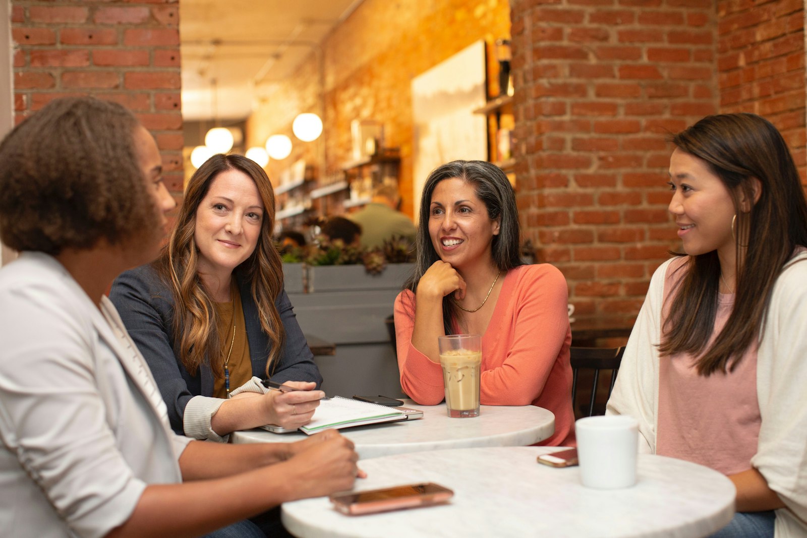 Quatre femmes discutent et sourient autour d'une petite table dans un café