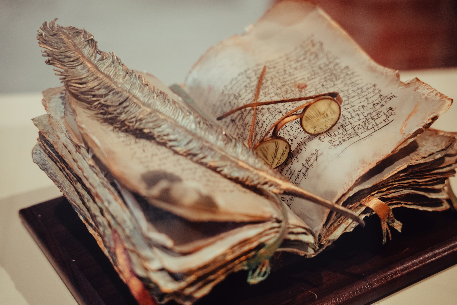 Vieux registre manuscrit aux pages jaunies, avec une plume et une paire de lunettes rondes posées dessus