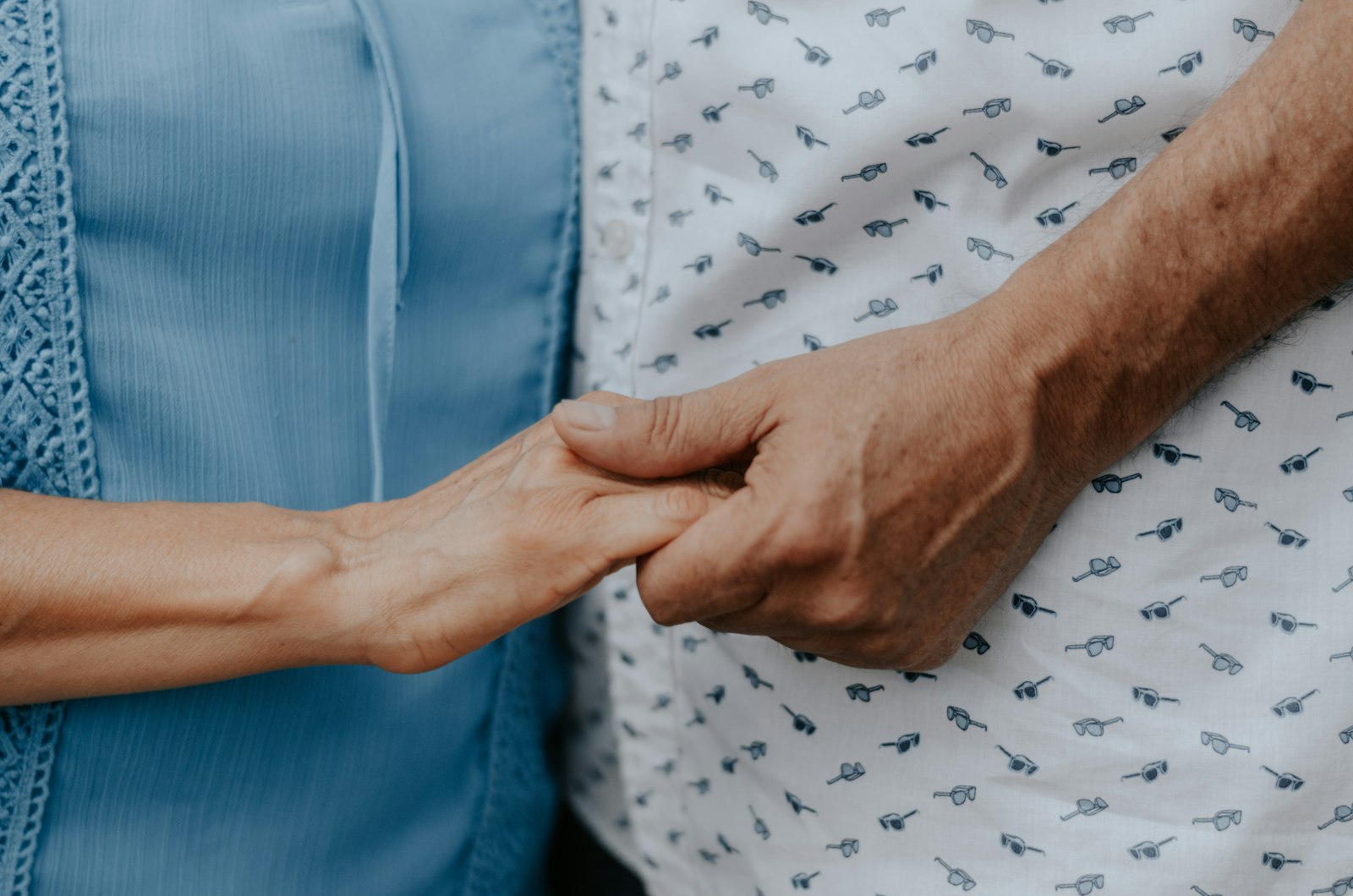 Deux mains se tiennent : celle d'une personne âgée et celle d'un proche, un geste de soutien tout en douceur