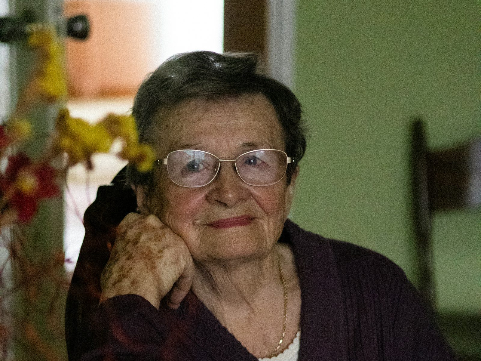 Une femme âgée au regard serein et souriant, le menton posé sur la main